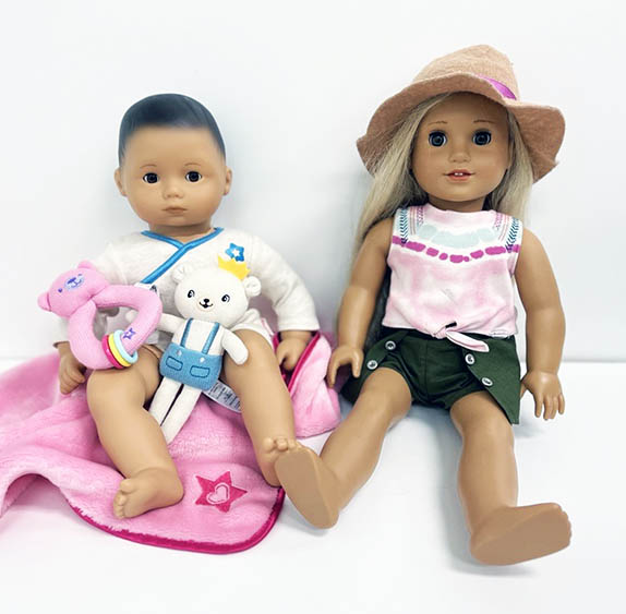 American Girl Doll in summer clothing with Itty Bitty Babay doll sitting on a pink blanket
