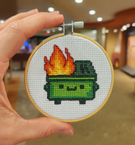 cross stitched dumpster fire in wooden hoop